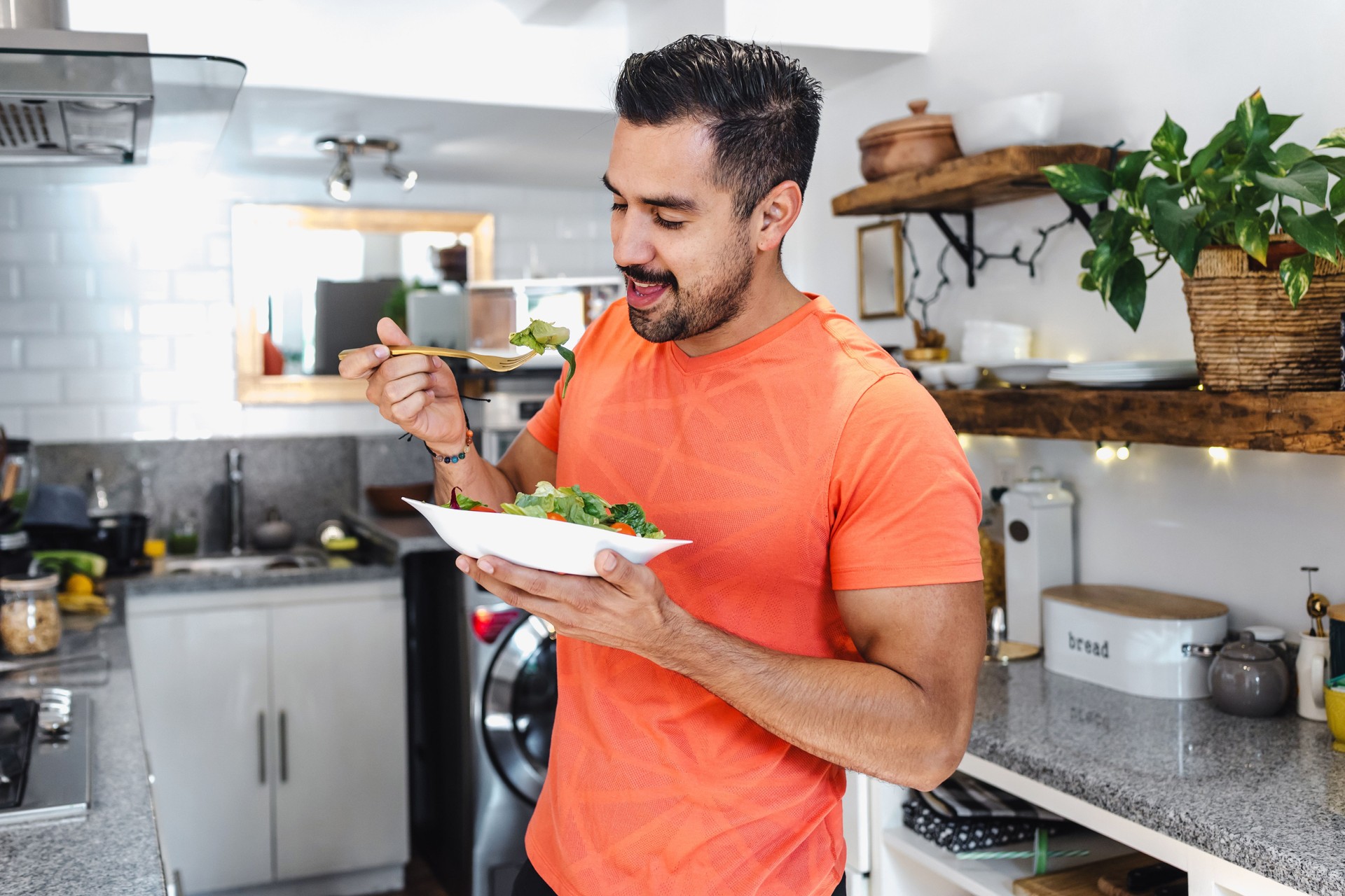 Latin man eating salad in kitchen at home in Mexico Latin America. Healthy hispanic male