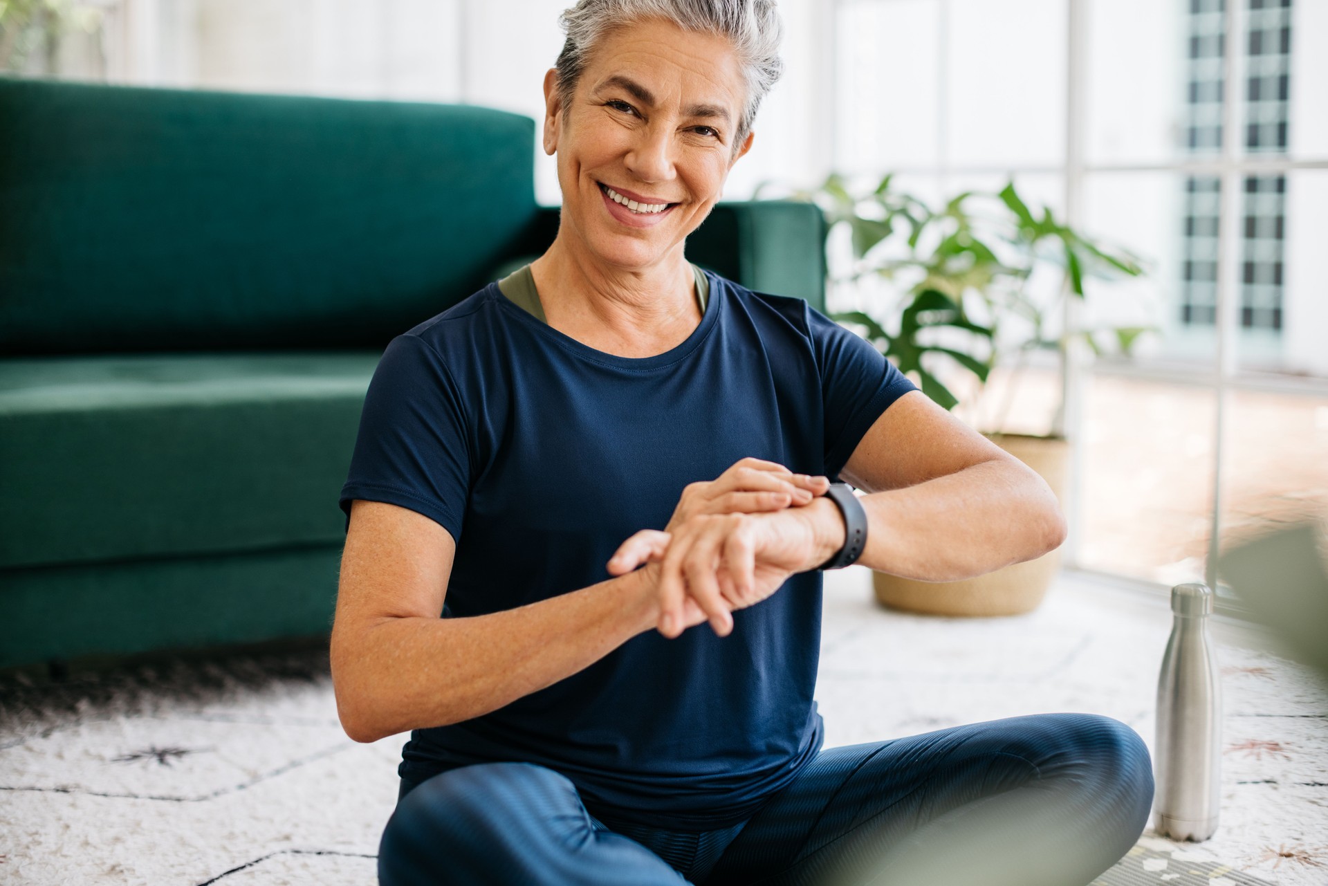 Fitness tracking with a smartwatch: Happy senior woman monitoring her heart rate during yoga